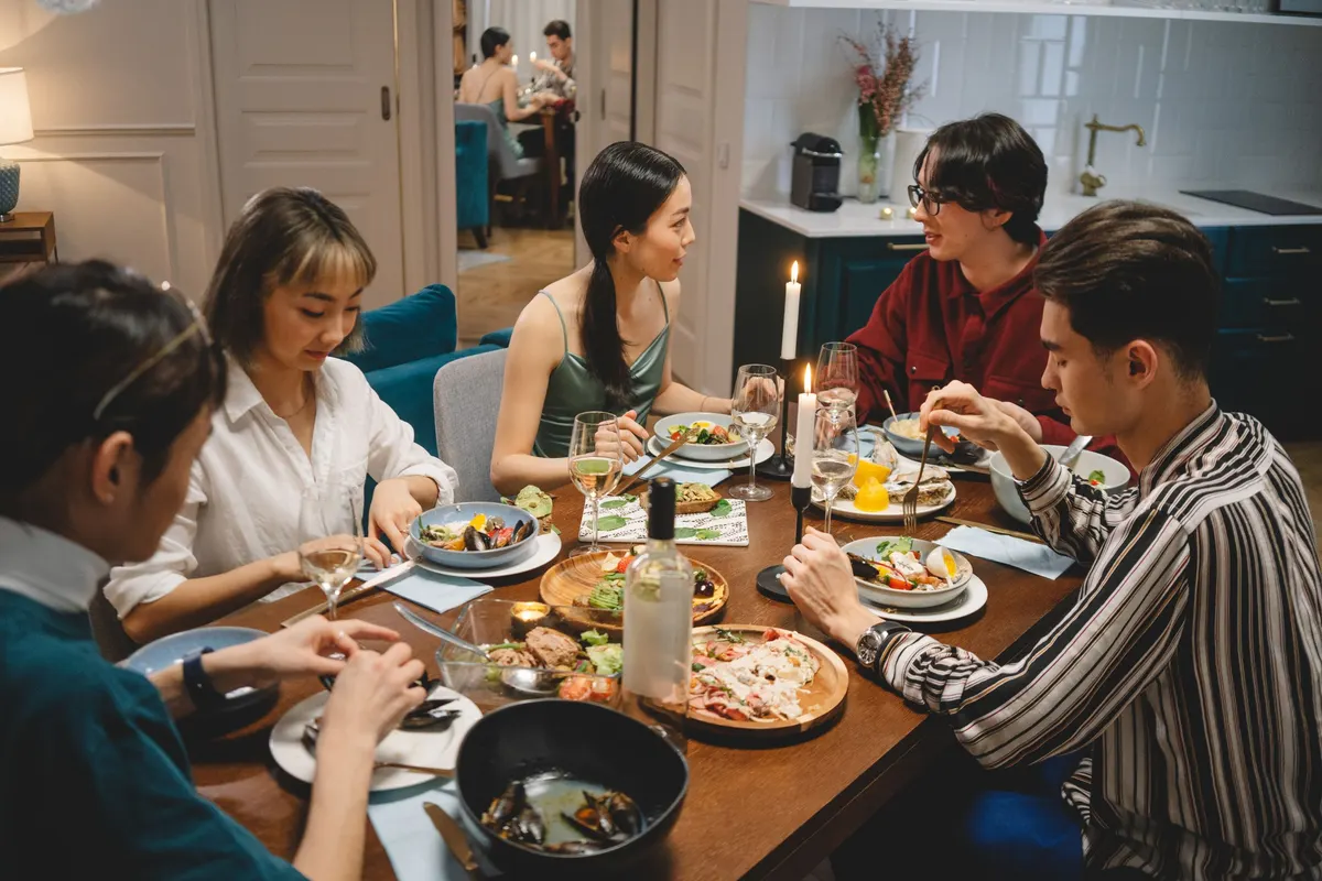 A small group in conversation around a dinner table in warm light